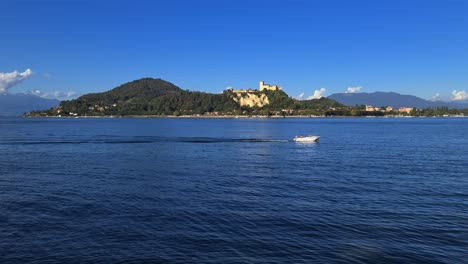 小型摩托船在意大利的梅戈雷湖平静的湖水中航行,背景是安吉拉城堡