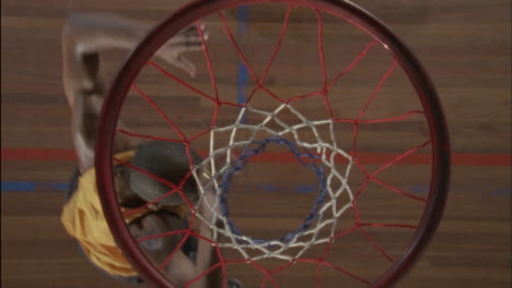 a basketball player hangs onto the hoop after the ball goes through then drops and walks away