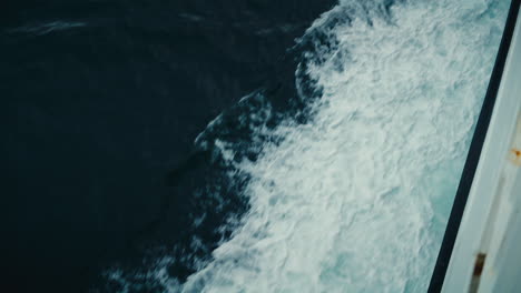 Slow-motion-shot-of-white-waves-splashing-on-the-surface-of-the-water-from-a-boat