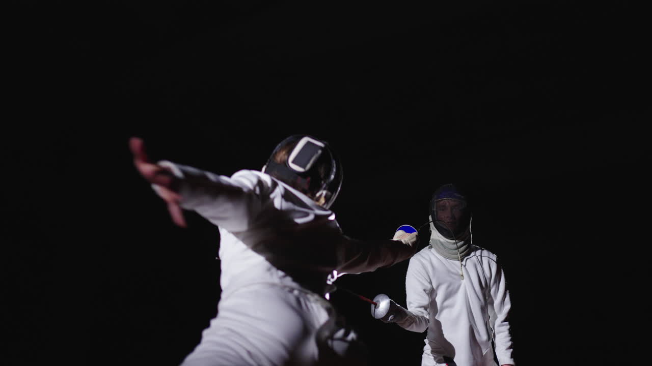 Two fencers compete in a fencing match