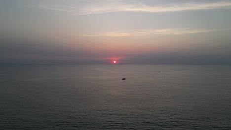 Boats-on-calm-sea-as-sun-sets-in-distance