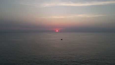 barcos en el mar tranquilo mientras el sol se pone en la distancia