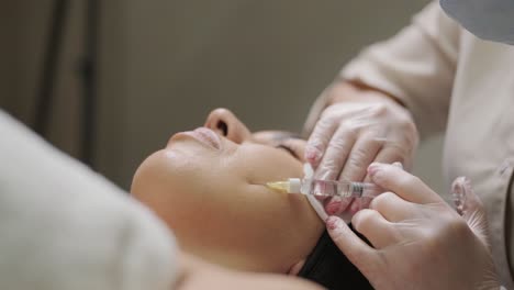 un paciente se reclina mientras recibe una inyección facial de un clínico en un entorno de spa médico, destacando el tratamiento estético sin centrarse en marcas específicas