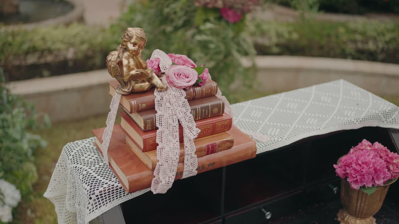 Stack of antique books with golden cherub and pink roses as decorative arrangement