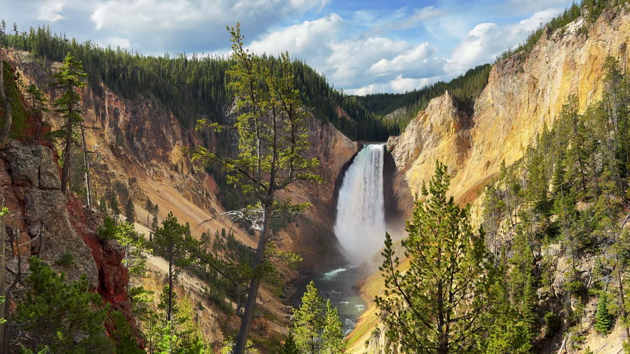 Air terjun Grand Canyon Sungai Taman Nasional Yellowstone, Air Terjun Atas dan Bawah, dengan pemandangan HDR dari titik pandang seniman saat musim gugur. Terlihat jalan menuju penginapan Canyon Village, lanskap siang hari yang menakjubkan, dengan gerakan pan sinematik ke kanan secara perlahan.