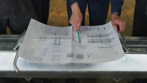trabajadores que revisan los planos para un proyecto de estructura metálica