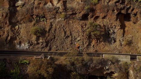 In-this-tracking-video,-a-male-cyclist-is-seen-conquering-a-mountain-road.-His-cycling-training-takes-place-on-a-sunlit-day-along-a-hilly-highway-road