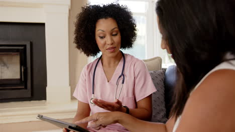 nurse in pink scrubs discussing health information with patient using tablet