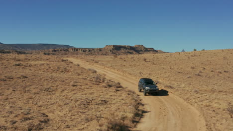 aerial as toyota 4runner suv drives offroad in desert landscape