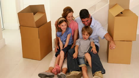 una familia feliz sentada en el suelo de su nueva casa