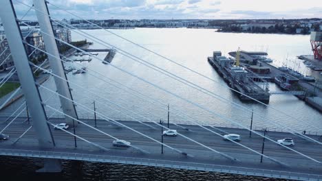 Cars-drive-across-cable-stayed-Crusell-Bridge,-Helsinki-blue-afternoon