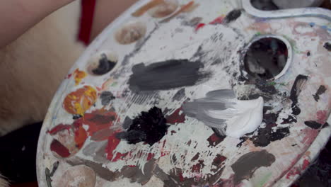 hand of artist mixing paint on white color palette, close up view