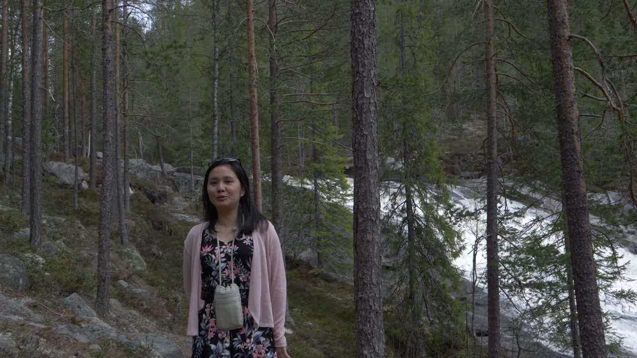 la chica lanza besos y camina por el bosque, cerca de una cascada