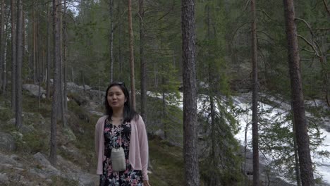 Girl-blows-kisses-and-walks-around-in-the-forrest,-near-a-waterfall