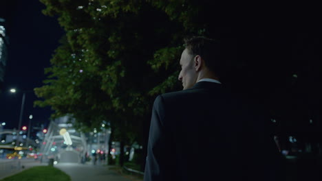 following shot of a man in suit walking outside office building while returning home during evening time