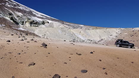 mountain aerial pulls out to reveal truck parked on summit ridge