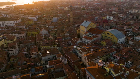 Volando-Sobre-Estructuras-De-Techo-Rojo-En-La-Histórica-Ciudad-De-Venecia,-Italia-Durante-La-Puesta-De-Sol