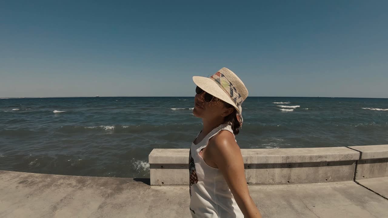 모자와 선글라스를 쓴 20대 행복한 소녀가 해변 부두에서 놀고 돌아다닌다