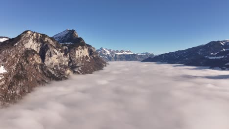 dense fog in the mountains of the canton of glarus in the swiss alps. the sun shining on the mountains from an aerial view