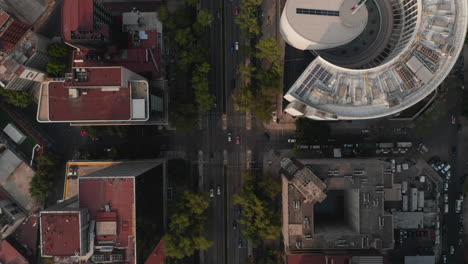 Aerial-birds-eye-overhead-top-down-view-of-traffic-in-city-streets.-Drone-camera-following-multilane-straight-road-between-tall-buildings.-Mexico-city,-Mexico.