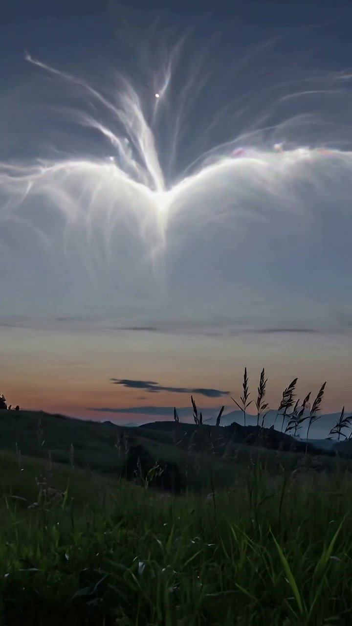 Vertical video: Launching bright arc sending column fanning into plumes on hillside orb trailing