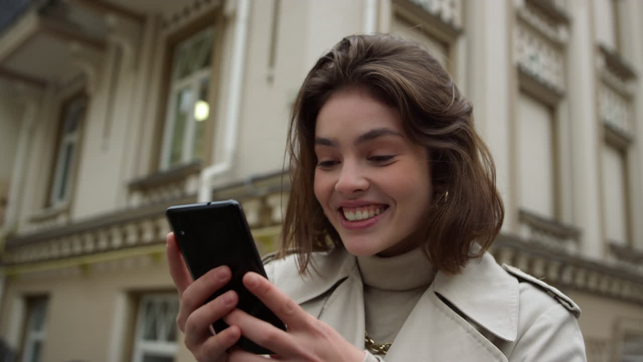 mujer emocionada haciendo una videollamada en la ciudad. chica feliz usando la cámara del teléfono al aire libre.