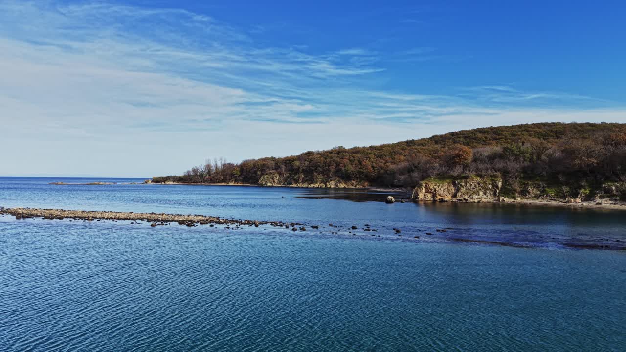 Seaside view of rocky shoreline under clear blue sky at midday