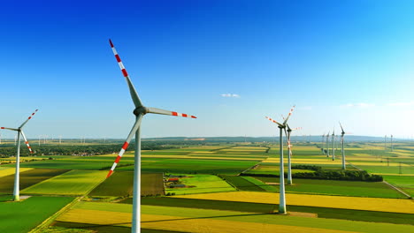 green agricultural plantations with multiple wind turbines. clean energy production. aerial view.
