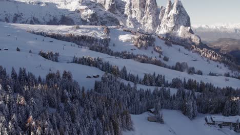 Antena-De-La-Estación-De-Esquí-Alpe-Di-Siusi-Durante-El-Amanecer-Con-Grandes-Acantilados-De-Montaña-En-El-Fondo,-Antena