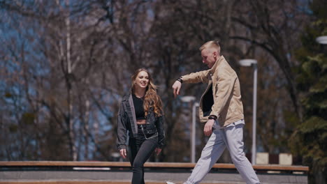 happy young couple spend time outdoors. beautiful girl enjoys the time with her positive boyfriend in the street. teenagers having a date in the park.