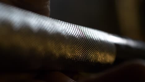 hand grabbing weightlifting bar, close up of barbell knurling, narrow depth of field