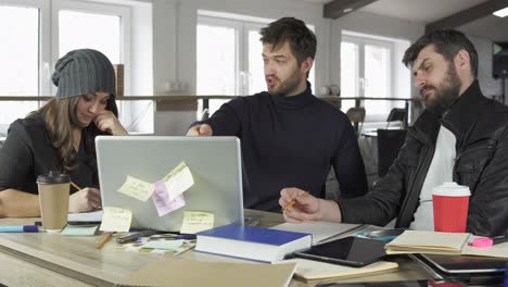 team of young professionals having a meeting in a creative office. team leader explaining the task. coffee cups and laptop on the table. shot in 4k