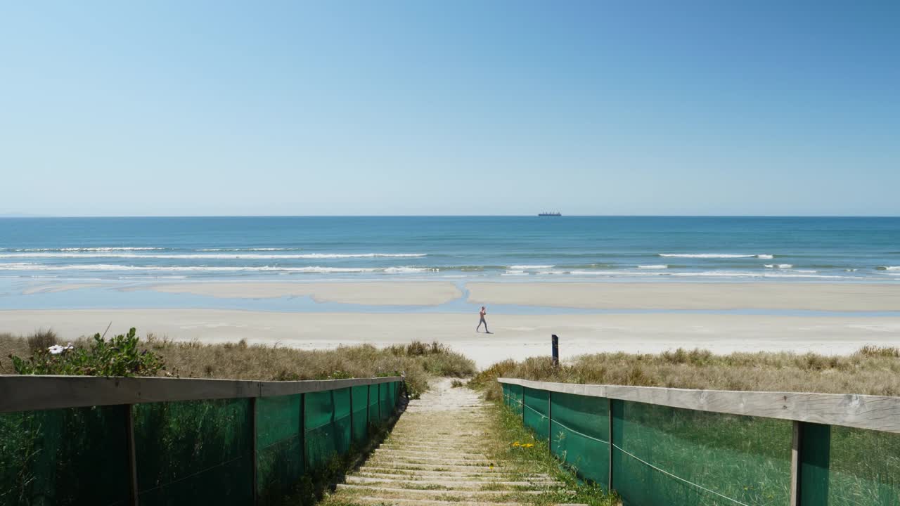 Man walking on golden sandy beach in new zealand