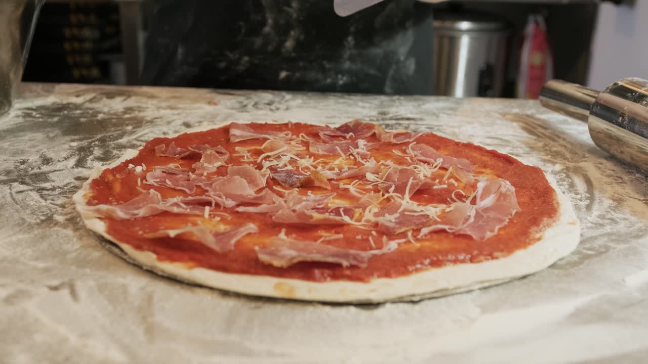 요리사는 피자를 만들고 치즈를 뿌립니다.