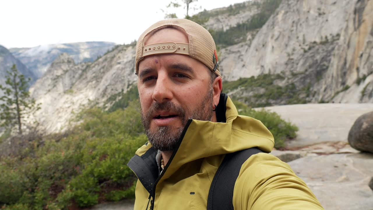 Uomo avventuroso che fa vlogging e gesticola in un paesaggio montano