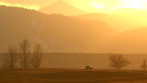 suv driving along a country road against a backdrop of mountains and sunset