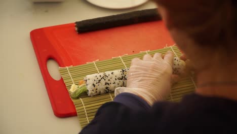 Slowmo-–-Japanischer-Koch-Bereitet-Sushi-Rollen-Mit-Lachs,-Avocado-Und-Sesam-Zu