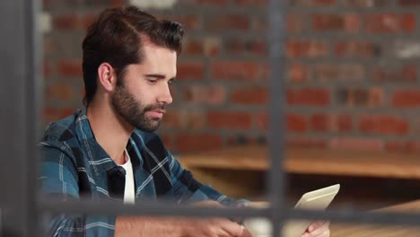 Lächelnder-Hipster-Mann,-Der-Ein-Tablet-Benutzt-Und-Kaffee-Nippt