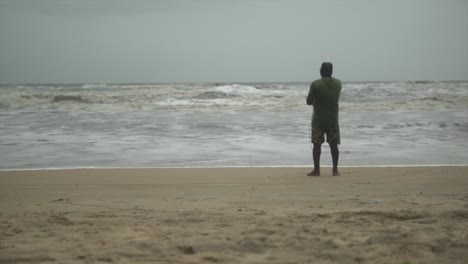 hombre con la espalda en la orilla de una playa pescando con una línea