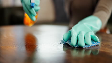 woman cleaning a table with gloves