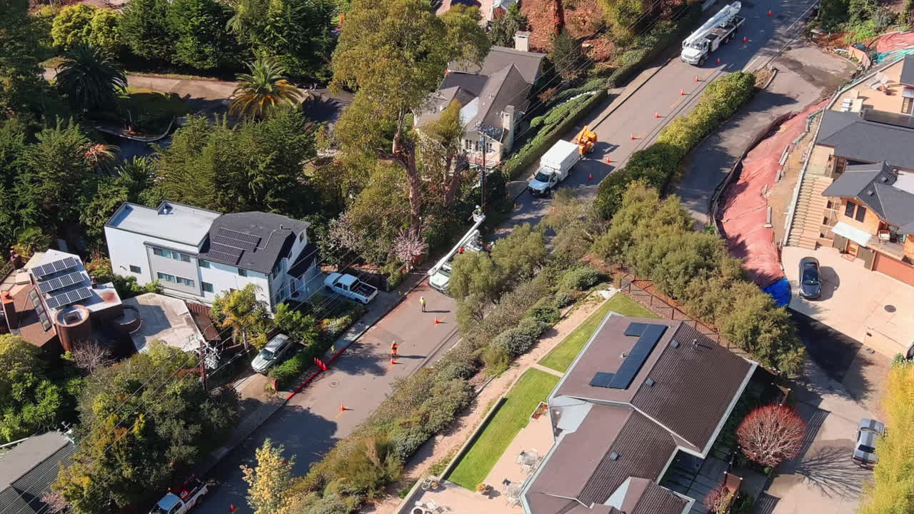vista cinematográfica de arriba hacia abajo del mantenimiento de la línea eléctrica en un suburbio acogedor