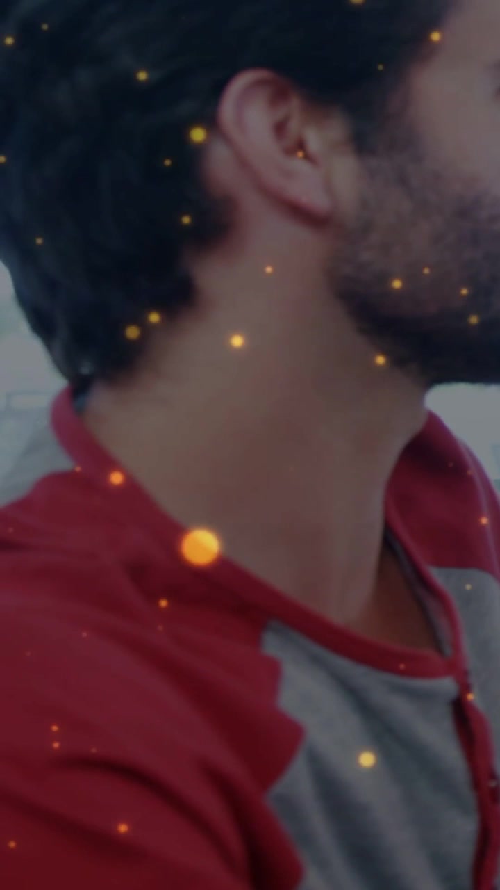 Vertical video: Seated man turning head right, revealing window, sparks drifting in front for ads