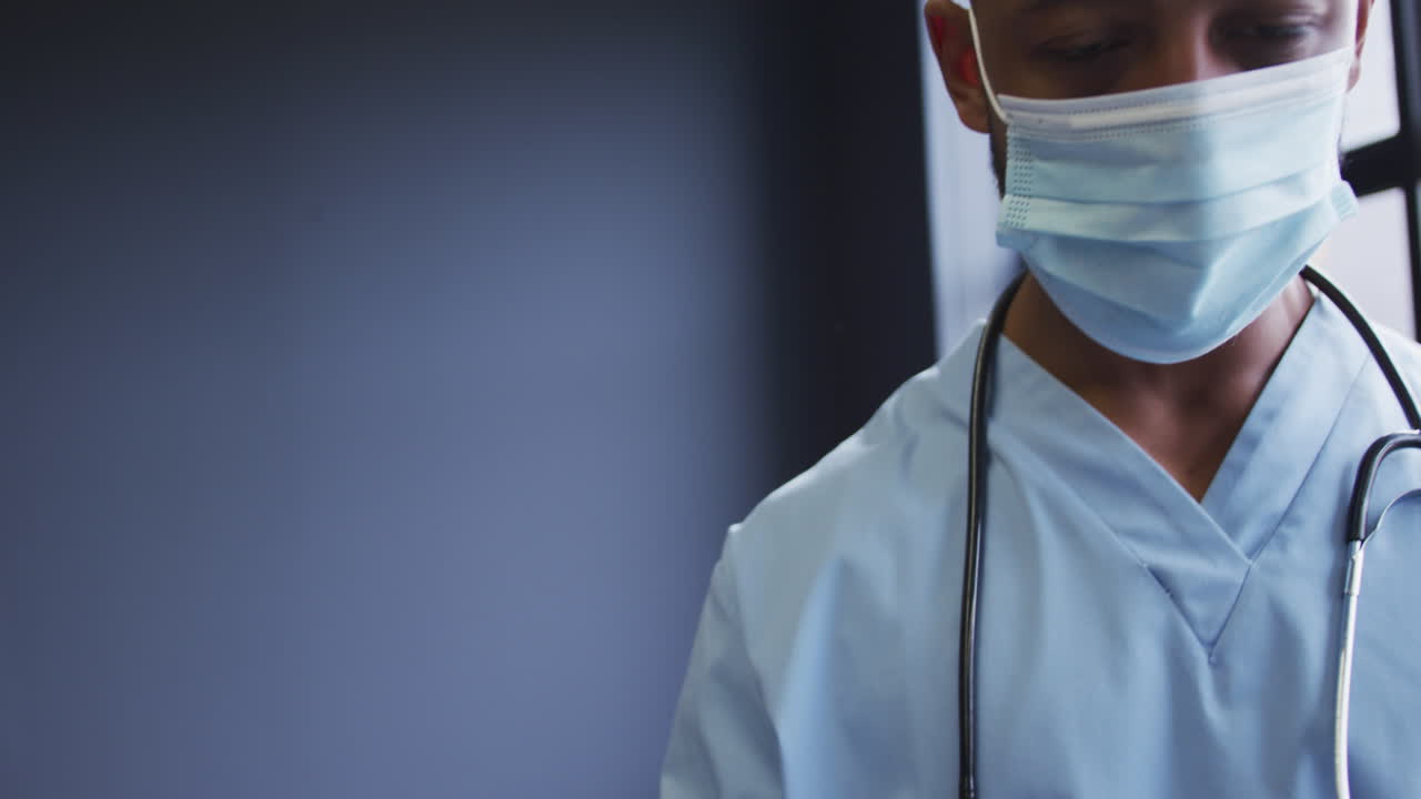 Biracial male doctor taking face mask of