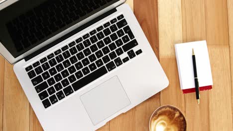 close-up of laptop with coffee cup and notepad