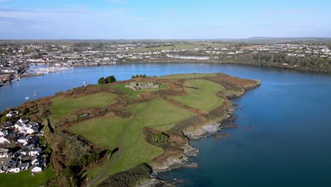 the view from above over horseshoe bend of river bandon in kinsale, ireland with green fields of a peninsula with an old fort, james fort