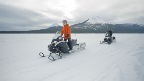 Toma-De-Seguimiento-En-Cámara-Lenta-De-Dos-Personas-En-Motos-De-Nieve-En-Un-Lago-Congelado