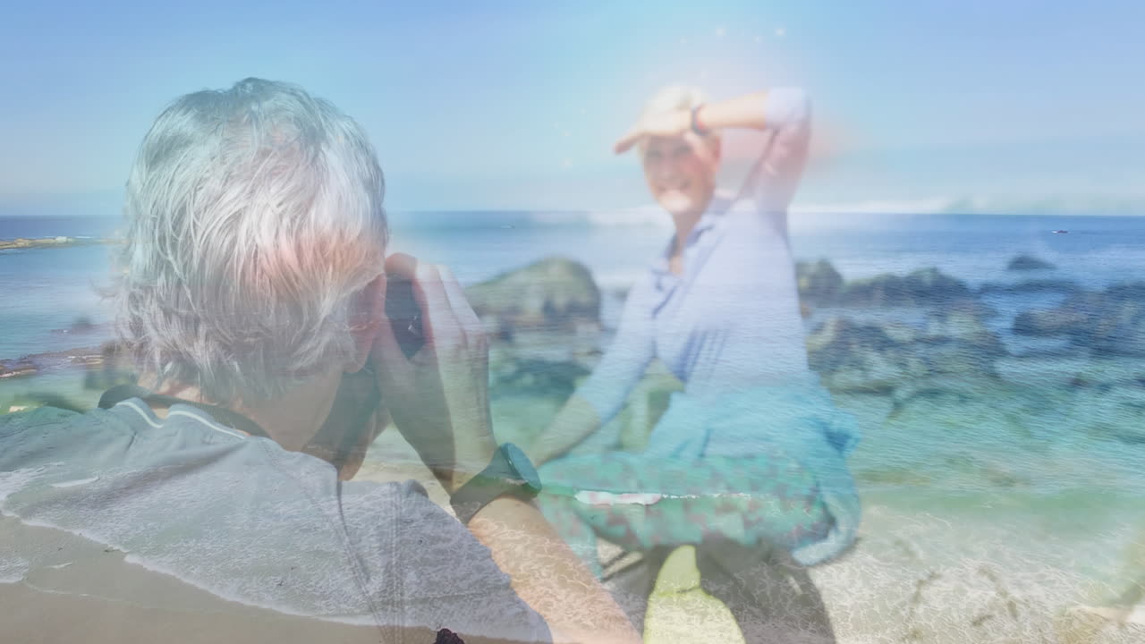 행복한 백인 노인 부부가 바다 파도 위의 해안에서 사진을 찍고 있습니다.