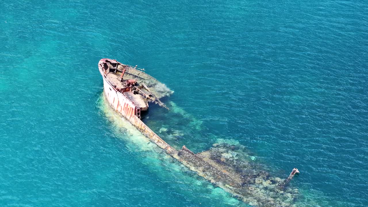 Una ripresa aerea con drone rivela un relitto arrugginito che riposa in acque tropicali limpide e turchesi