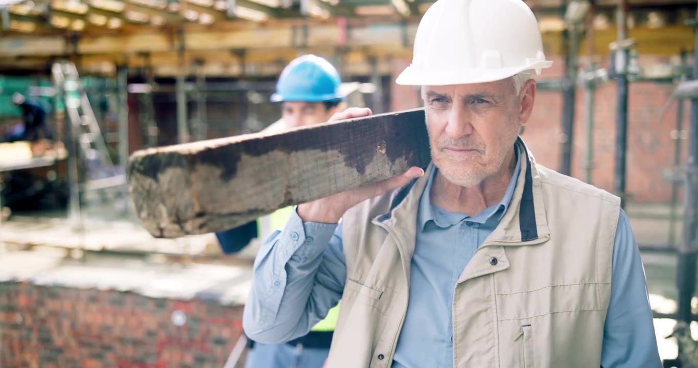Operai edili che trasportano travi di legno nel cantiere