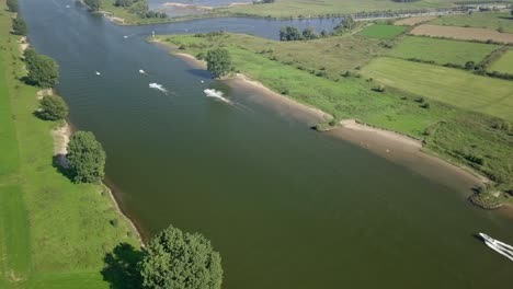 Aerial-drone-view-of-the-Meuse-river-and-some-boat-passing-by-in-the-Netherlands,-Europe